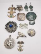 A large collection of silver and white metal Mexican, Mayan and Aztec design brooches, pendants