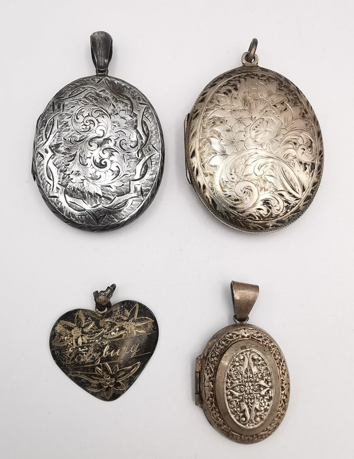 A collection of a three silver lockets and a Swiss engraved silver heart pendant. One locket