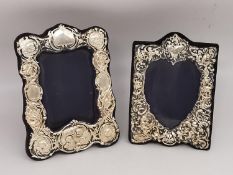 Two Victorian style repousse silver easel picture frames, one with a heart shaped picture cut out.