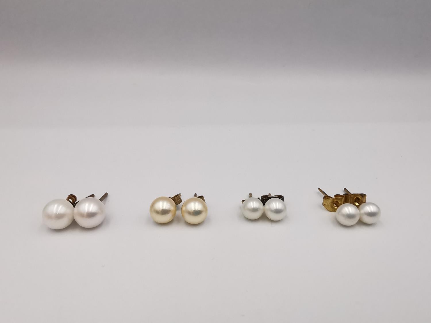 Four pairs of round cultured pearl stud earrings, three pairs with 9ct posts and butterflies. One