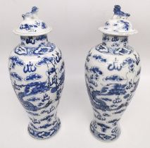 A pair of 19th century Chinese blue and white lidded dragon vases. Each vase decorated with four