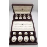 Two leather cased sets of eight novelty silver place card holders, four modelled as a lady's straw