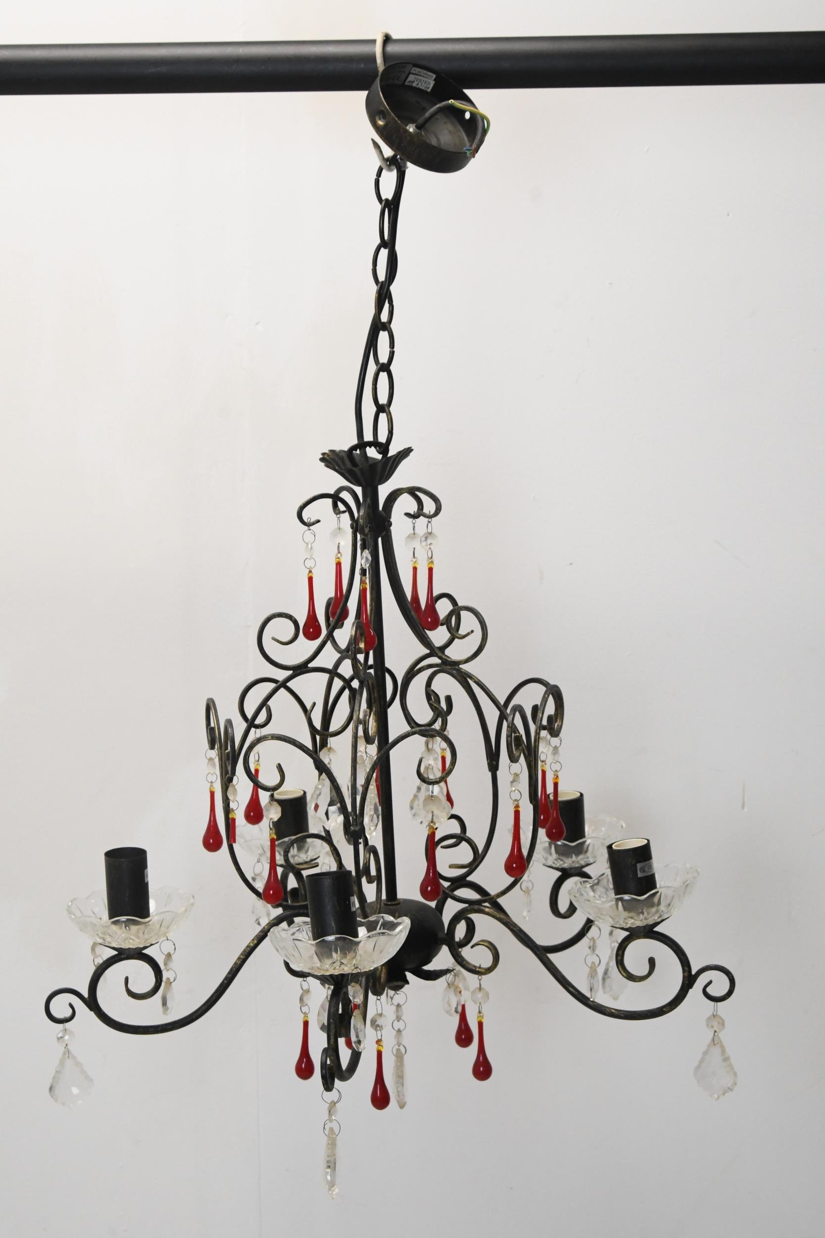 A wrought iron chandelier with five scrolling branches and ruby and cut crystal drops. H.70 W.45cm.
