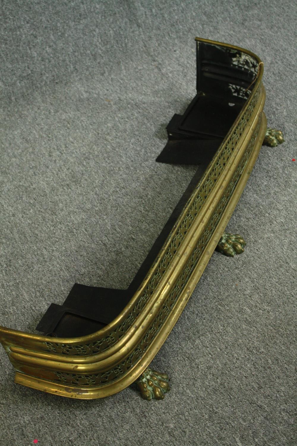 An early 20th century pierced brass fender with vine motifs and three lion paw feet. H.23W.105 D. - Image 2 of 4