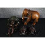 A cherub sconce lamp with A carved elephant and a pair of carved Chinese faces. H.39cm. (largest)