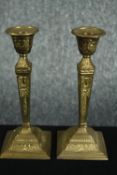 A pair of brass candle holders with an ornate laurel and ribbon raised relief. H.21cm. (each)