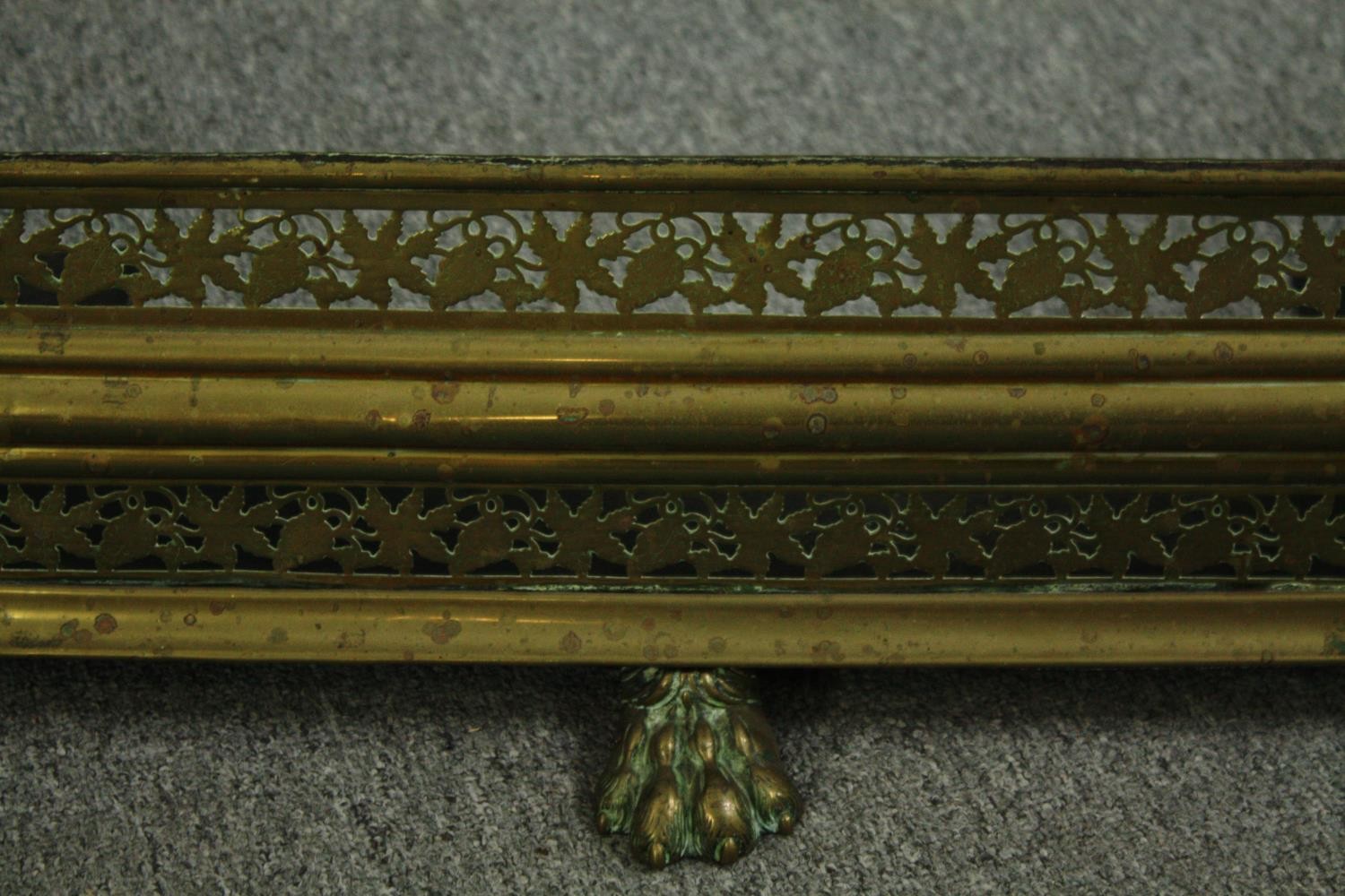 An early 20th century pierced brass fender with vine motifs and three lion paw feet. H.23W.105 D. - Image 4 of 4