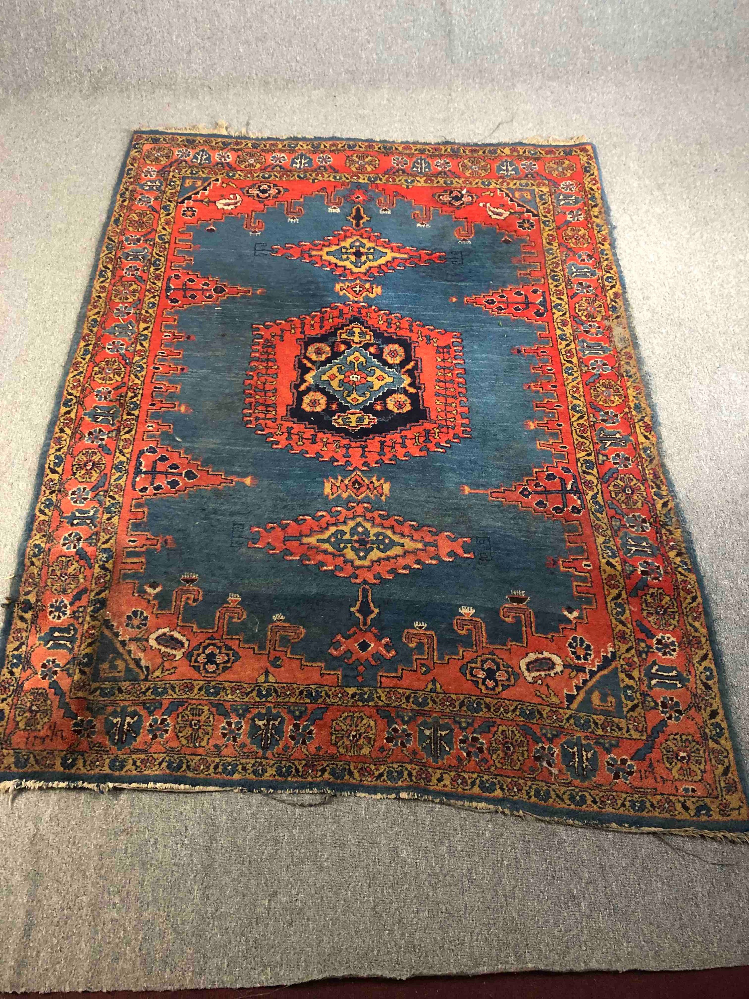 A Persian handmade Senneh rug with geometric designs, dominated by red on a dark blue ground. L.