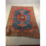 A Persian handmade Senneh rug with geometric designs, dominated by red on a dark blue ground. L.