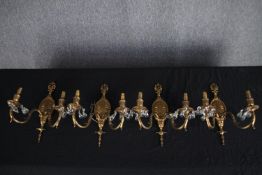 A set of four brass wall mounted twin branch wall sconces decorated with drop glass. H.38cm (each)
