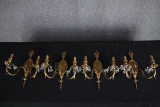 A set of four brass wall mounted twin branch wall sconces decorated with drop glass. H.38cm (each)