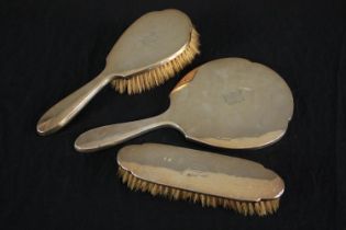 An Edwardian three piece silver brush and mirror set, with engraved monogram. Hallmarked: