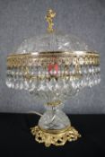 A gilt metal and cut crystal dome table lamp with crystal drop detailing and cherub finial. H.44