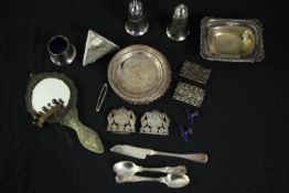 A mixed collection of white metal including a hand mirror, spoons, a silver nurses buckle, and a