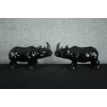 A pair of ceramic rhino figures. In a black painted glaze. H.23 W.40cm. (each)