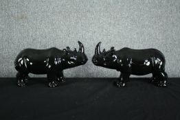 A pair of ceramic rhino figures. In a black painted glaze. H.23 W.40cm. (each)