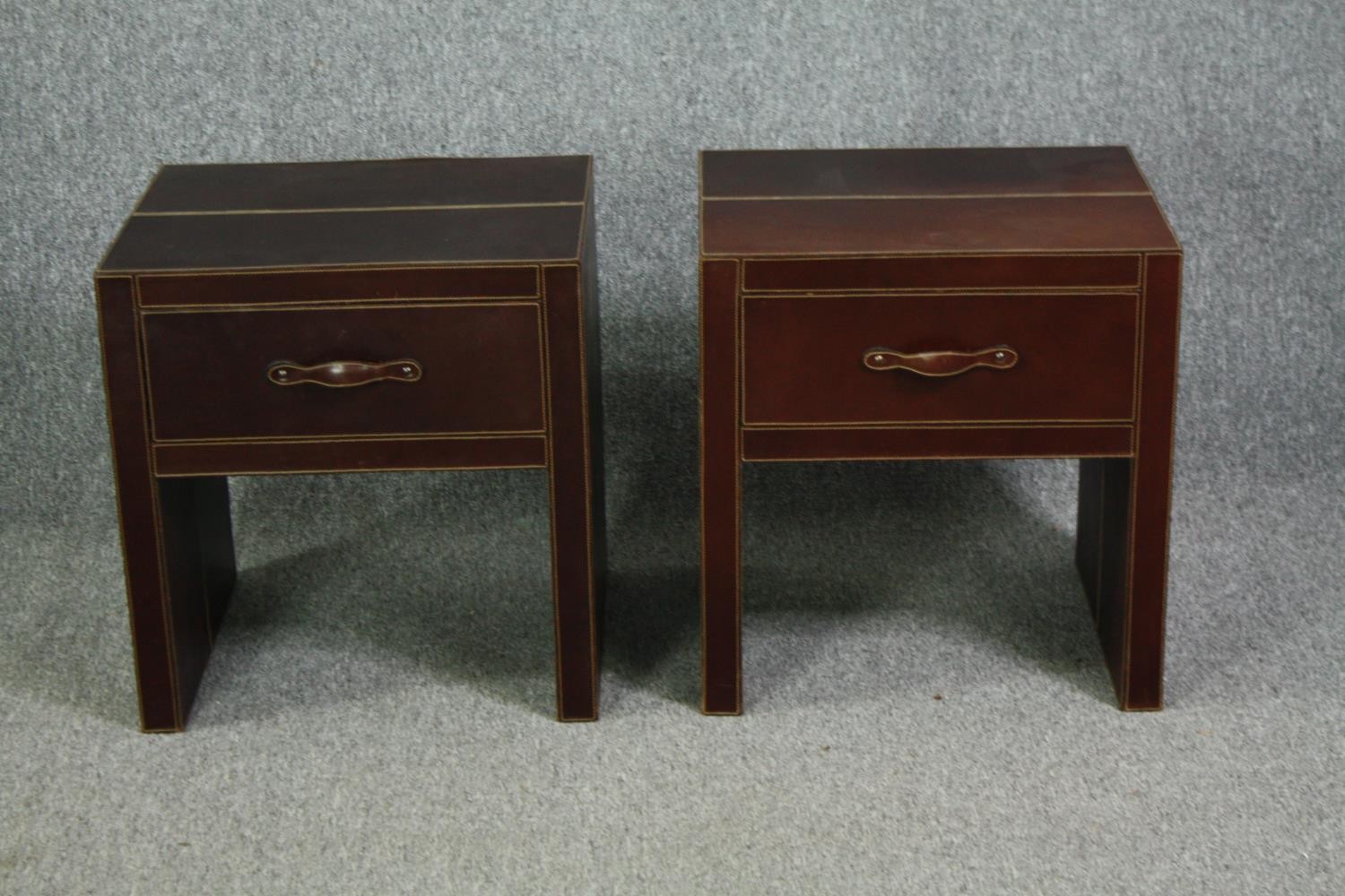 A pair of contemporary bedside cabinets covered in stitched leather. H.53 W.50 D.44cm.