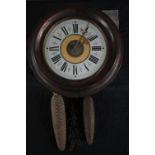 A 19th century Black Forest postman's alarm clock with black Roman numerals and fir cone weights.