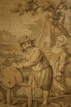 A framed and glazed early 20th century tapestry of a knife grinder and his wife by a mill house. H.