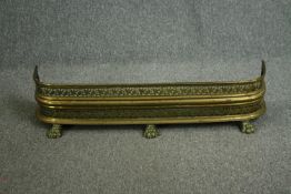 An early 20th century pierced brass fender with vine motifs and three lion paw feet. H.23W.105 D.