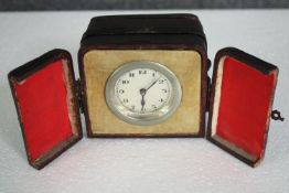 A 1930's wind-up travel clock in a leather case. H.8 W.10 D.9cm.