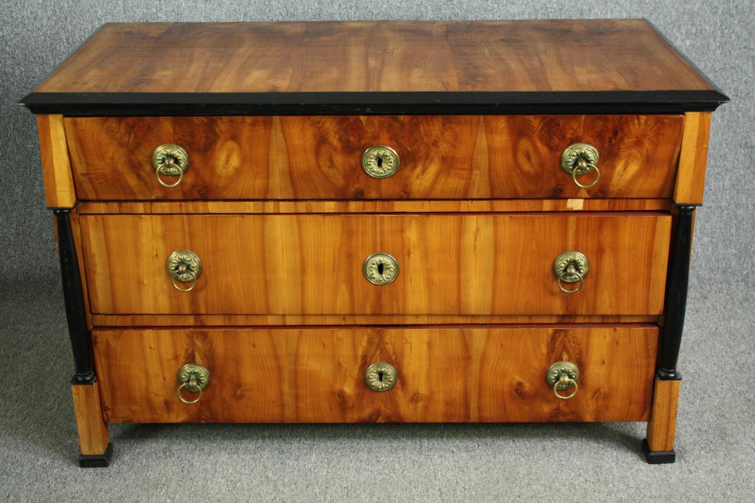 An early 19th century walnut Biedermeier chest of three long drawers flanked by ebonised pilasters