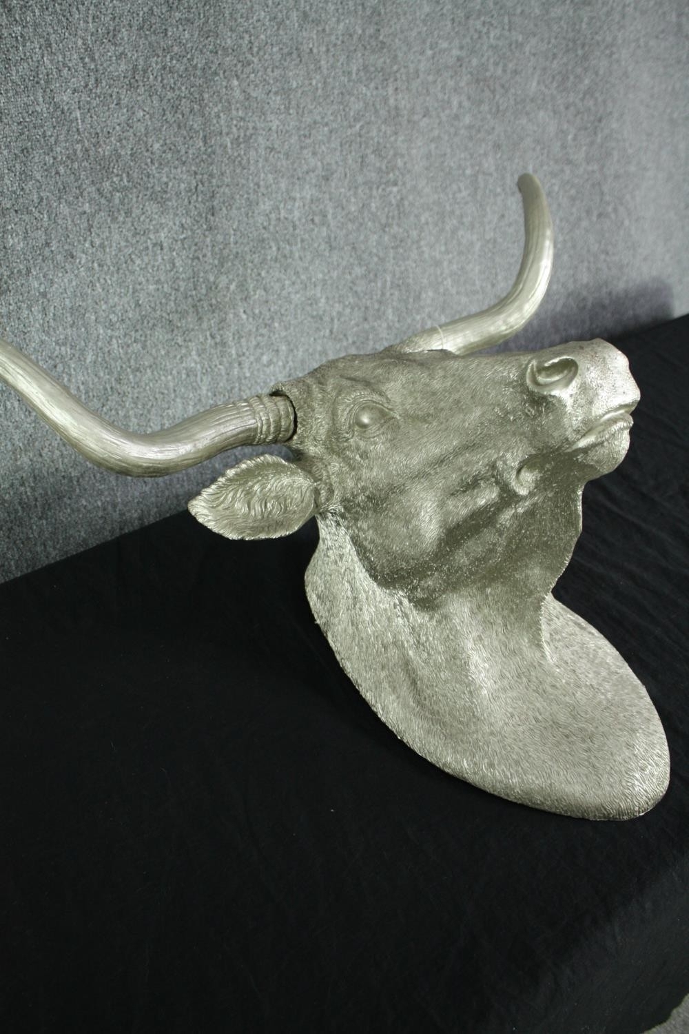 A fibreglass horned bulls head finished in silver. H.54 W.73cm.