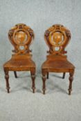 Hall chairs, mid 19th century oak with well carved shield backs above panel seats on turned tapering
