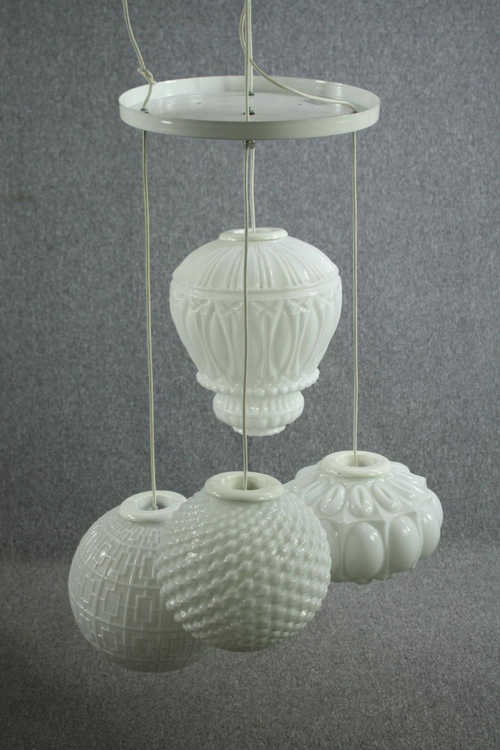 An arabesque chandelier by Mm Design. Four adjustable white glass shades each a different shape