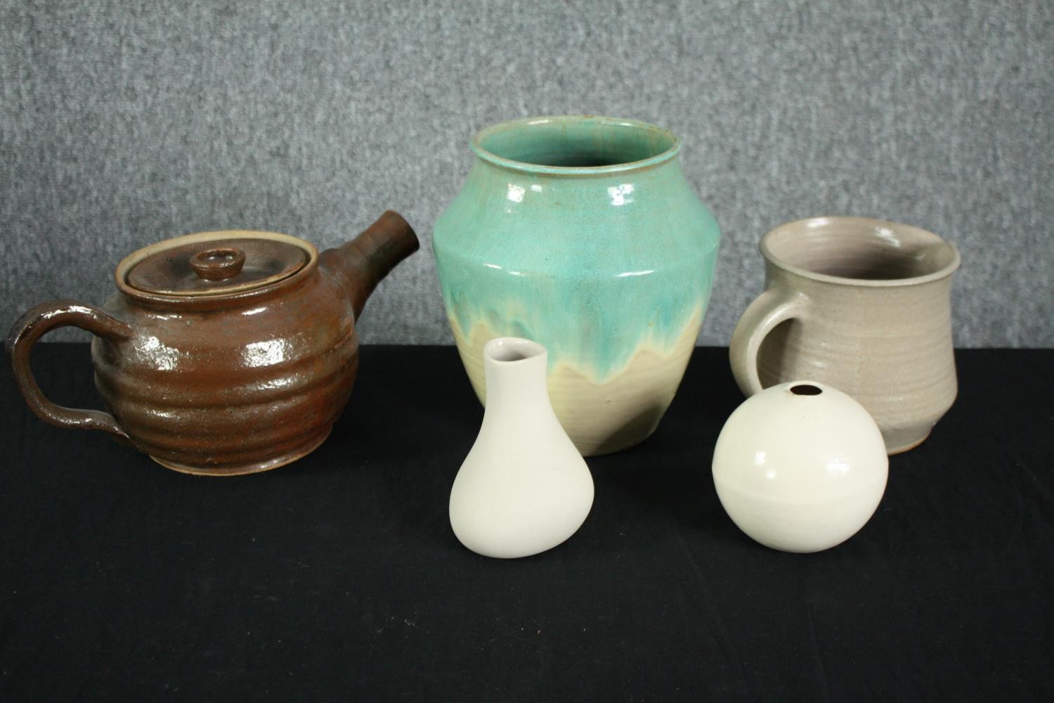 A mixed collection of pottery including a teapot with a flared spout, a jug, and three vases. The