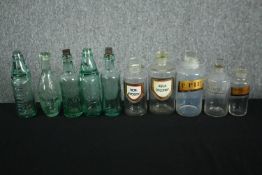 A collection of early 20th century apothecary jars and bottles, including five with name labels. H.