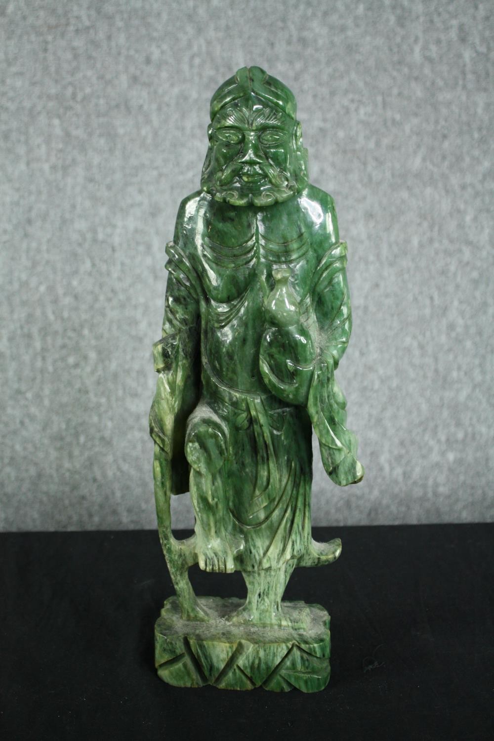 A 20th century carved spinach jade figure of a Chinese elder. H.43cm.