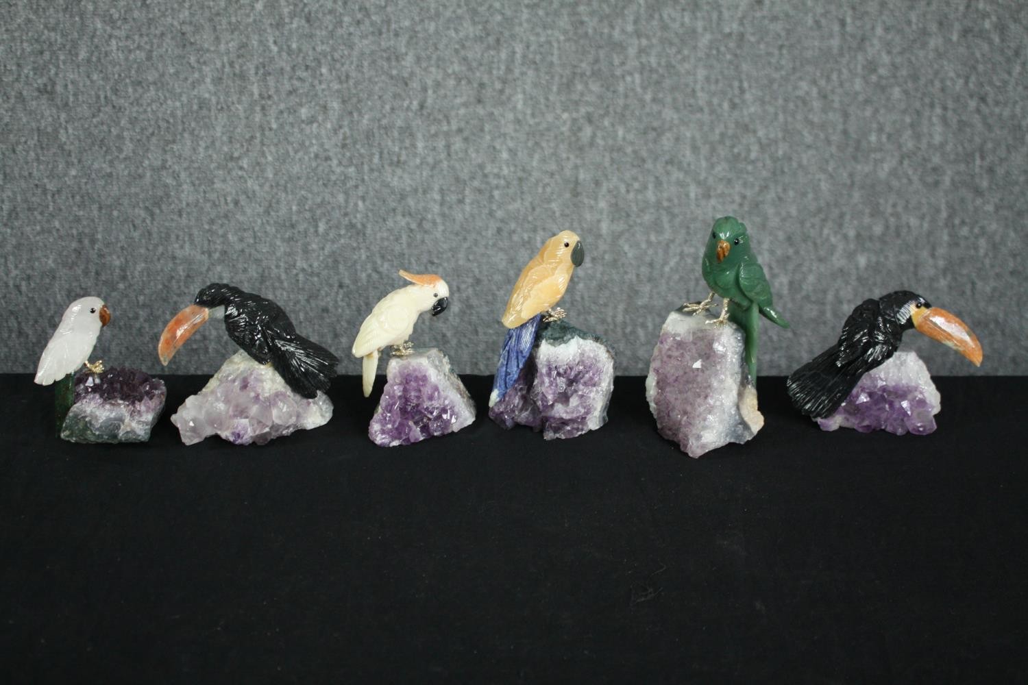 A collection of six pieces of amethyst mounted with detachable perched parrots carved from various