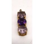 A 9ct yellow gold three stone amethyst and pale pink stone pendant by Tony Bestwick. The pendant set
