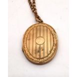 A 9ct yellow gold engraved locket and rolo link chain. The front and back of the locket engraved