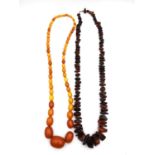 Two early 20th century amber necklaces, one graduated butterscotch amber beads (largest bead 2.6cm