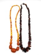 Two early 20th century amber necklaces, one graduated butterscotch amber beads (largest bead 2.6cm