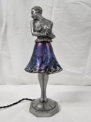 Art Deco spelter table lamp of a half nude lady in a flowing glass iridescent skirt, standing on a