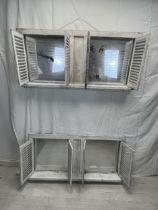 A pair of distressed painted window frames with louvre shuttered doors, each fitted with a pair of