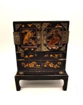 A late 19th century Japanese lacquered and gilded jewellery cabinet on stand. Each door decorated