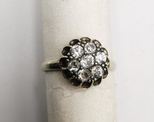 An early 20th century white metal (tests as 14 carat or higher) floral form diamond cluster ring.
