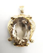 A 14 carat yellow gold engraved scrolling ribbon design smoky quartz set statement pendant. Set to