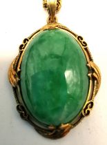 A vintage 14 carat yellow gold and jade pendant with fine curb link chain. The pendant set with a