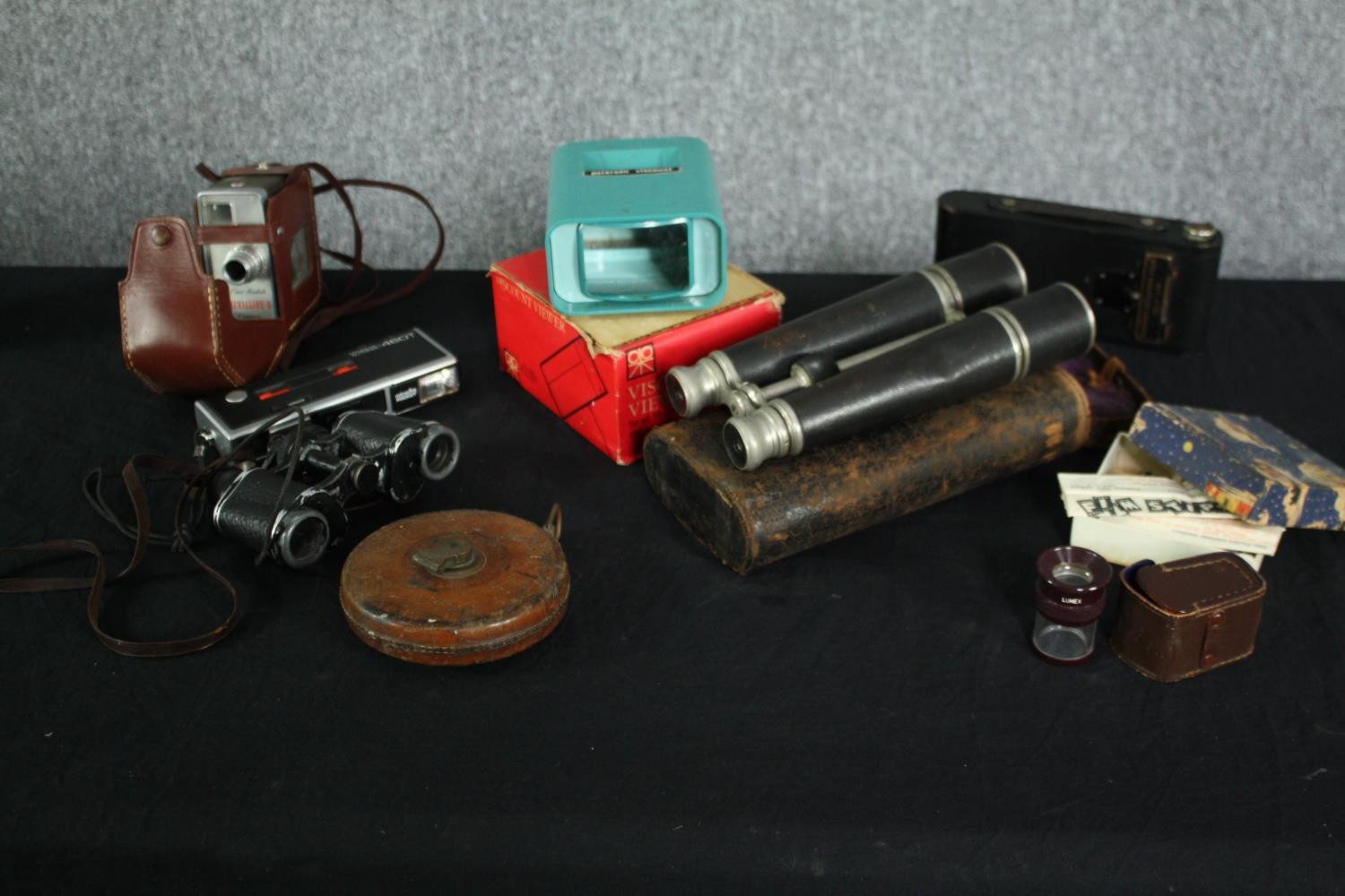 A collection of photographic and cinematic equipment and binoculars. Includes a Minolta Pocket