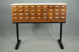 Filing cabinet, vintage teak with composite laminate top and a bank of thirty six drawers on a metal