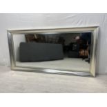 A large contemporary wall mirror in silvered frame. H.100 W.200cm.