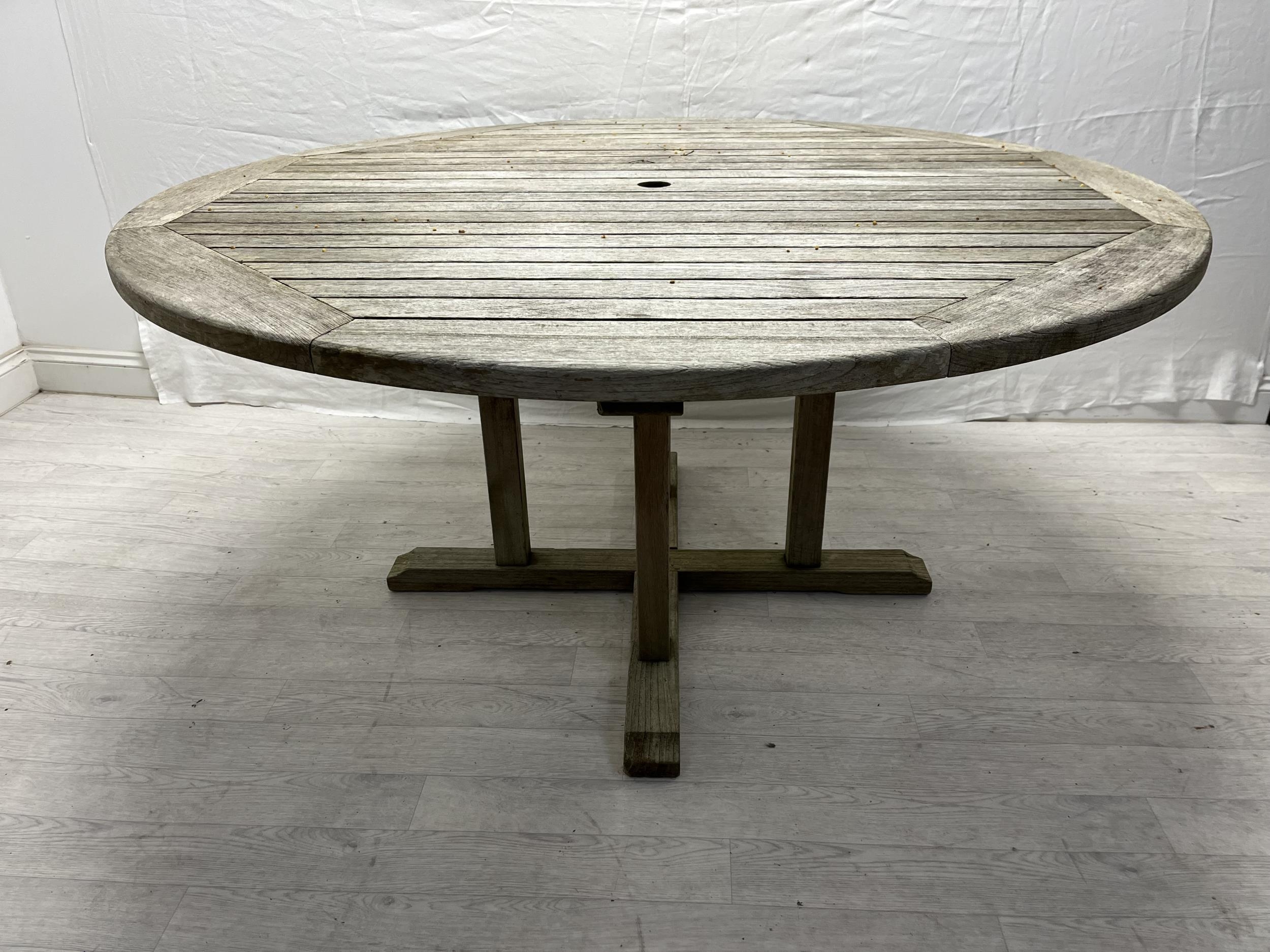 A vintage weathered teak garden table. H.72cm Dia.150cm.