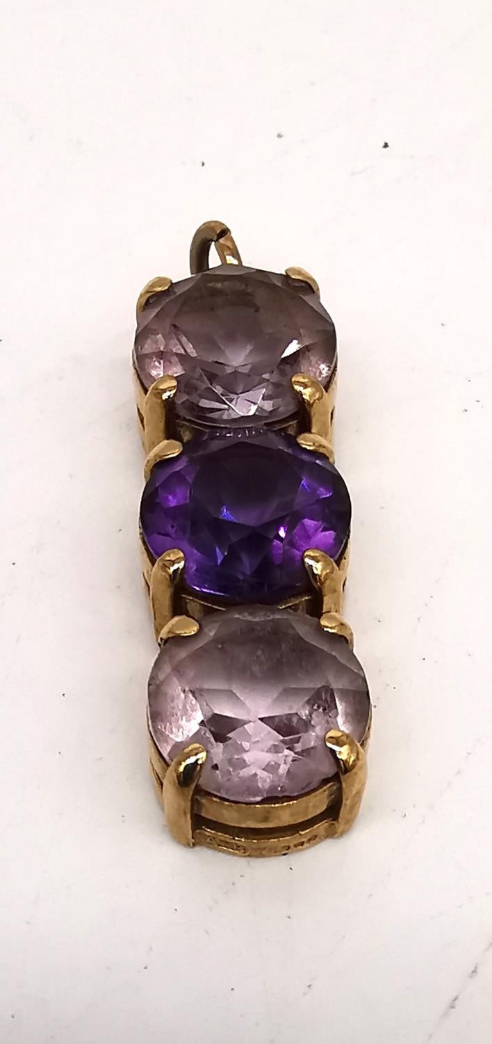 A 9ct yellow gold three stone amethyst and pale pink stone pendant by Tony Bestwick. The pendant set