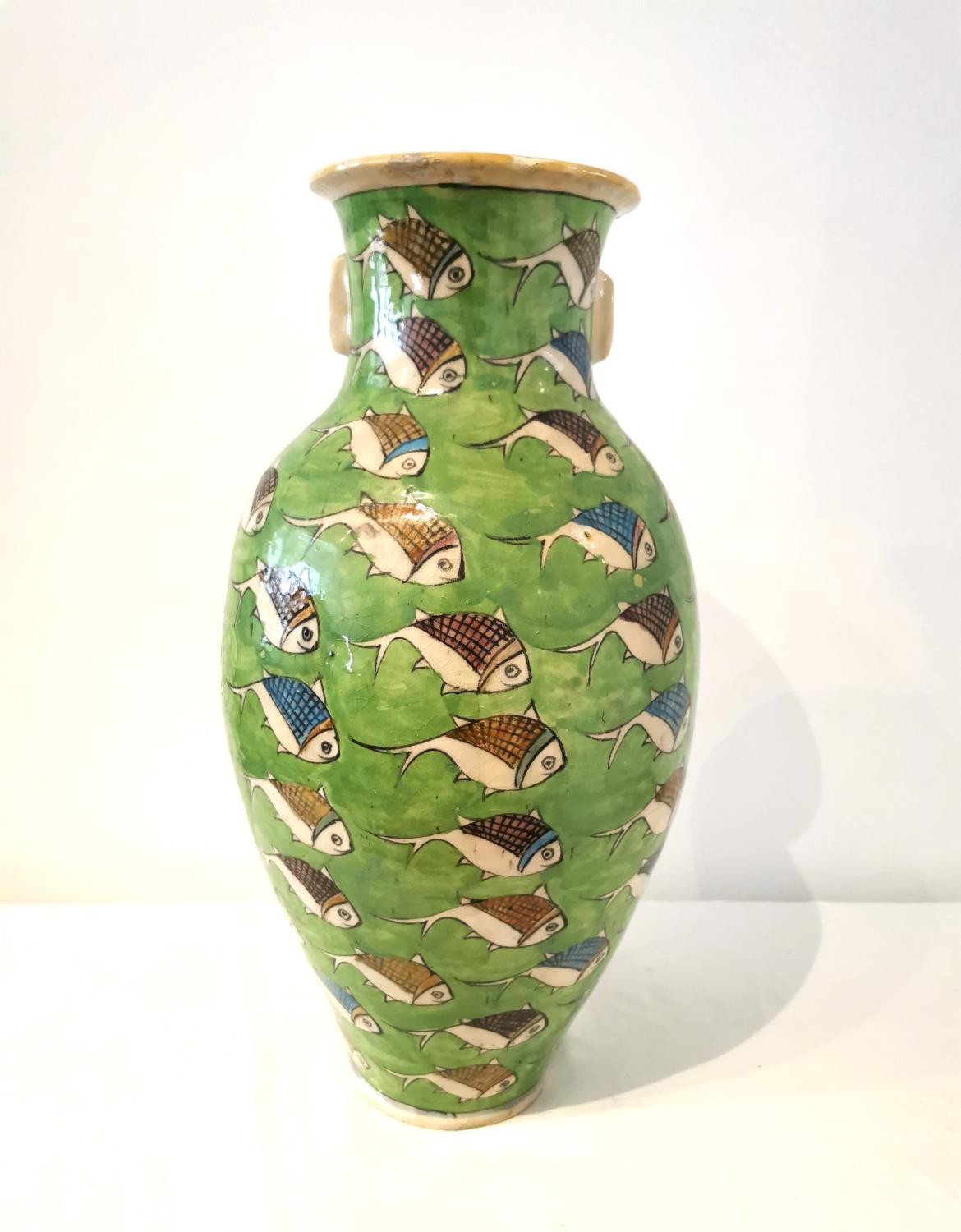 A large twin handled Persian Iznik ceramic vase with green ground and painted fish. H.54 D.25cm.