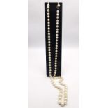 A long knotted string of graduated cultured pearls with 9ct yellow gold red stone set hook and